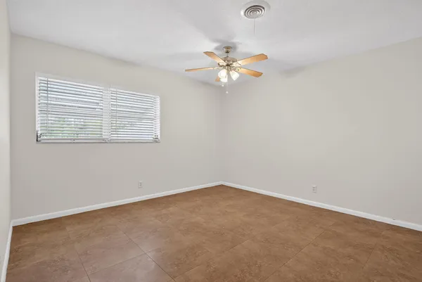 an empty room with a window and a fan