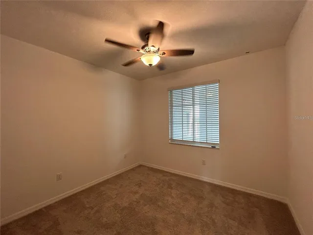 an empty room with a window and a fan