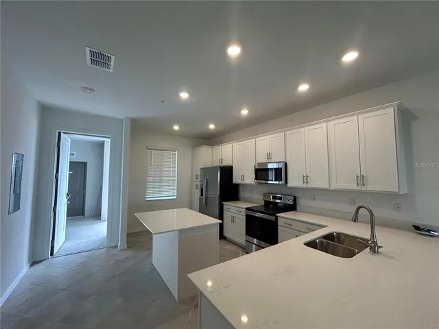 a kitchen with kitchen island a sink stainless steel appliances and cabinets