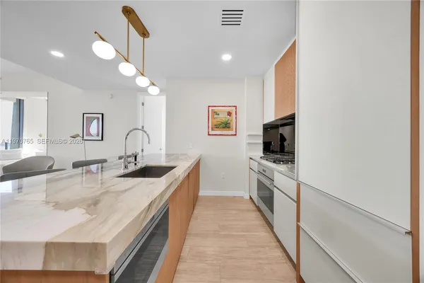 a large kitchen with kitchen island a sink stainless steel appliances and cabinets