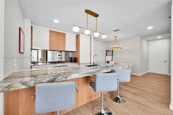 a kitchen with stainless steel appliances granite countertop a sink a stove top oven a dining table and chairs with wooden floor