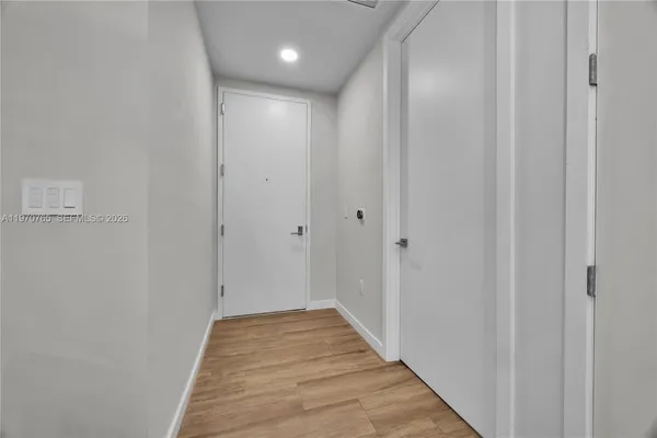 a view of a hallway with wooden floor and a bathroom