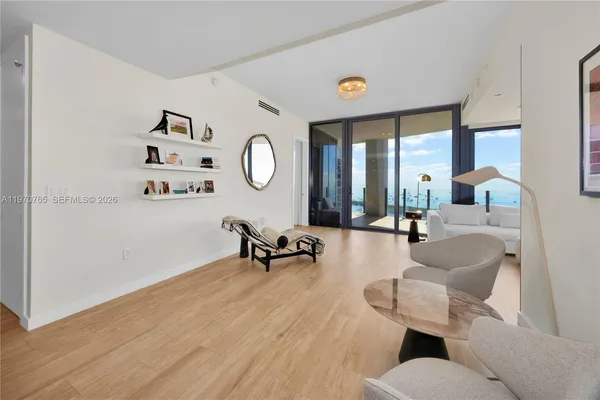a living room with couches a large mirror and a dining table with wooden floor