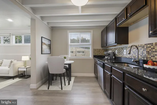 a kitchen with stainless steel appliances granite countertop a stove a sink dishwasher a microwave oven and a dining table with wooden floor