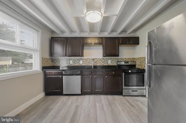 a kitchen with stainless steel appliances granite countertop a refrigerator a stove and a sink