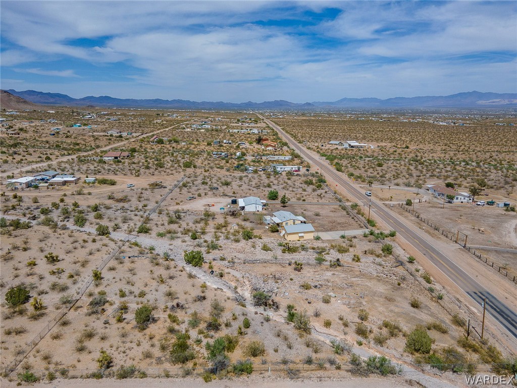2465 Egar Road Golden Valley, AZ 86413 - Photo 93 of 98 Expansive desert landscape with distant mountains under a blue sky, featuring a paved road and scattered properties