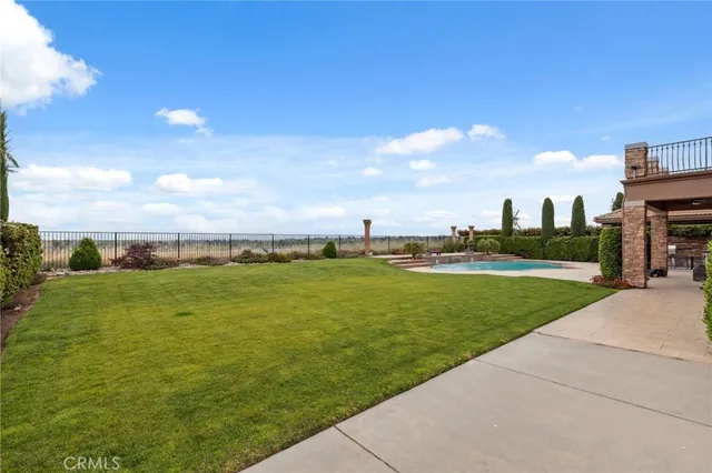 a view of a white house with a swimming pool and lawn chairs under an umbrella