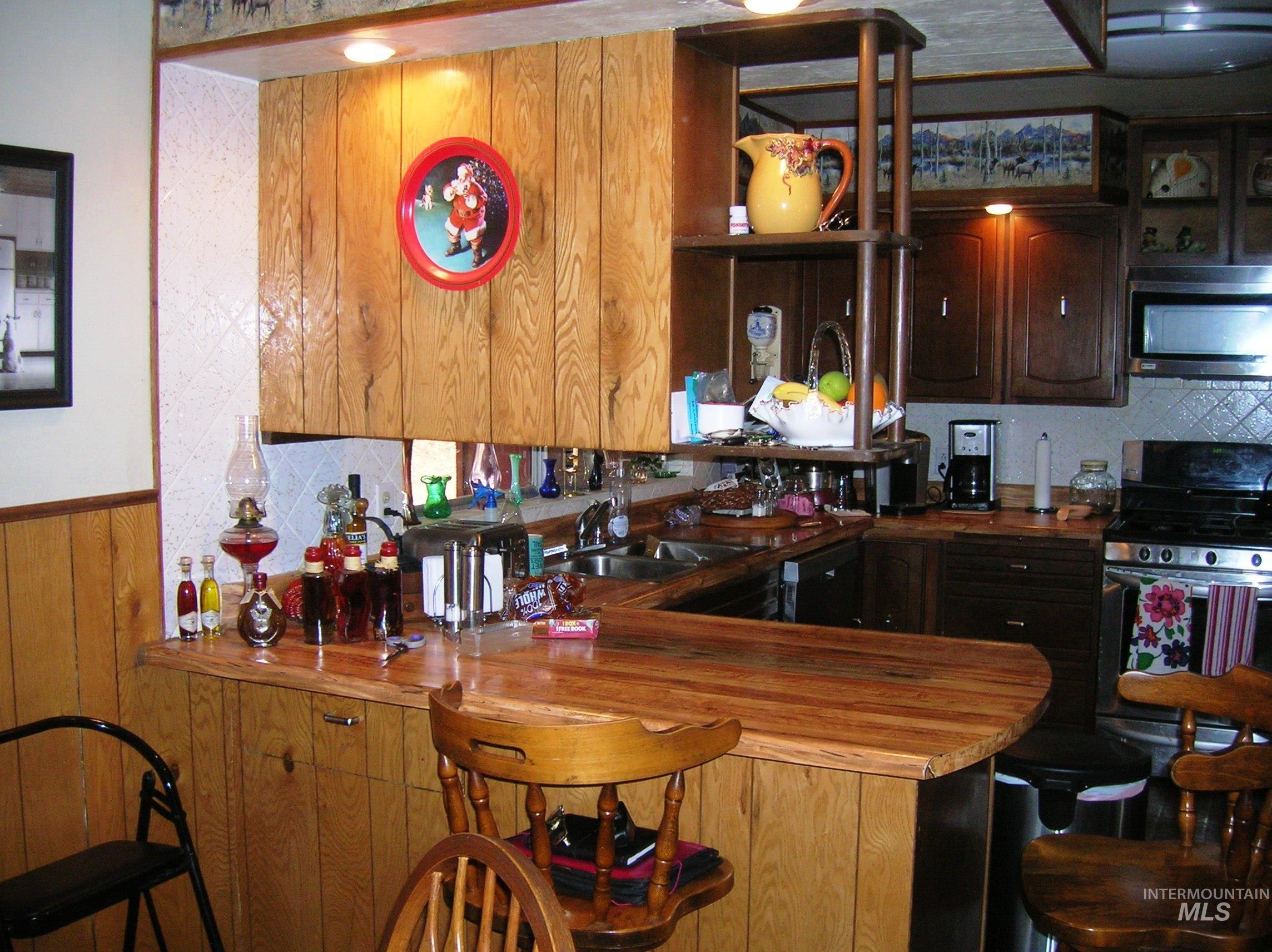 307 Locust Road Kamiah, ID 83536 - Photo 32 of 50 Kitchen with wood-finish paneling, an integrated breakfast bar, built-in shelving, recessed ceiling lighting, and dark wood cabinetry