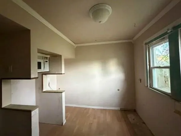 a view of empty room with window and wooden floor