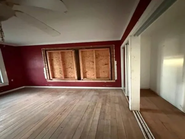 an empty room with wooden floor and windows