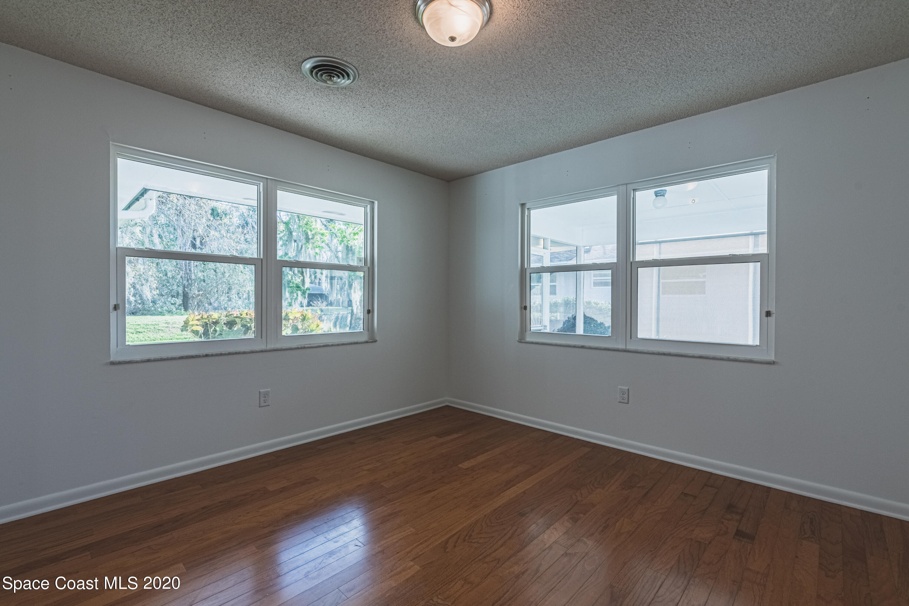 1945 Trimble Road Melbourne, FL 32934 - Photo 19 of 83 a view of an empty room with wooden floor and a window