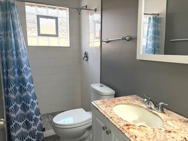 a bathroom with a granite countertop toilet a sink and a mirror