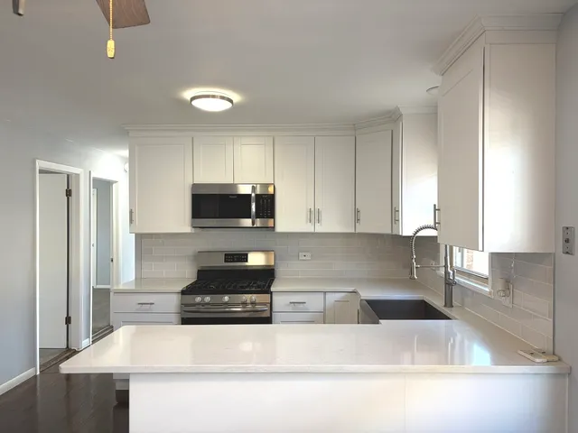 a kitchen with granite countertop a sink a stove a refrigerator and white cabinets