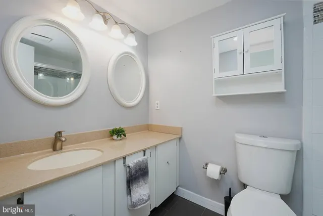 a bathroom with a granite countertop toilet a sink and a mirror