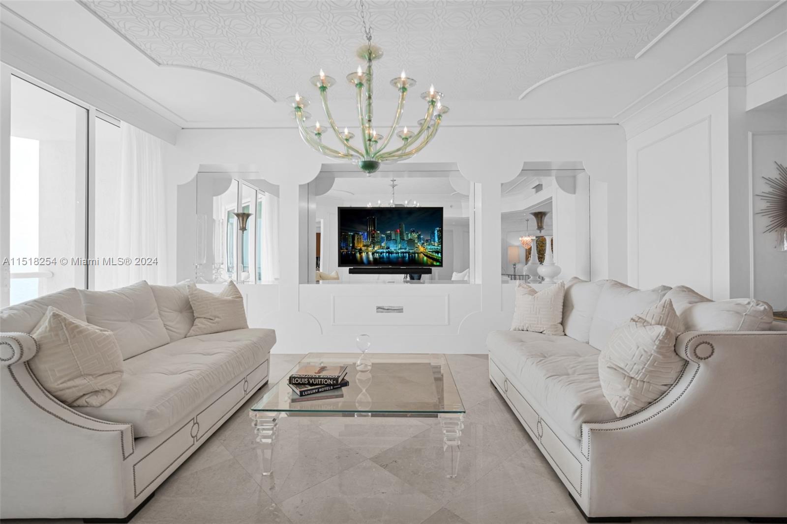 a living room with furniture a chandelier and a flat screen tv