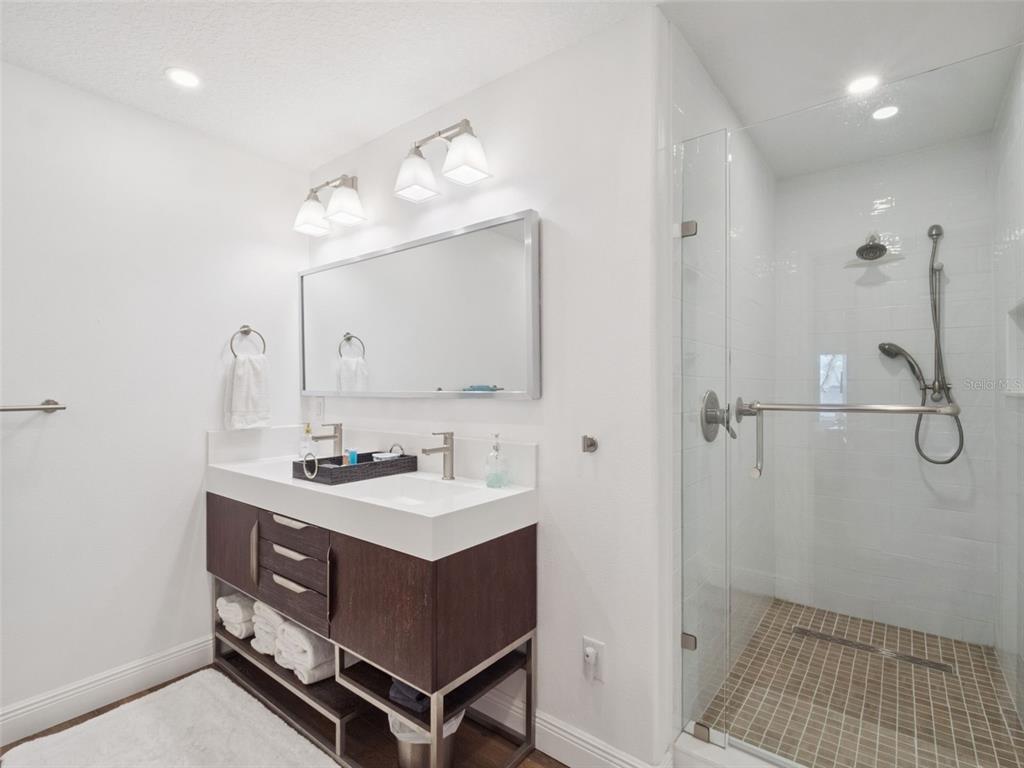 12943 Southeast Sunset Harbor Road Weirsdale, FL 32195 - Photo 45 of 65 a bathroom with a sink a mirror and shower