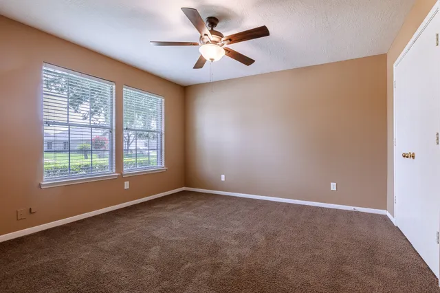 an empty room with windows and fan