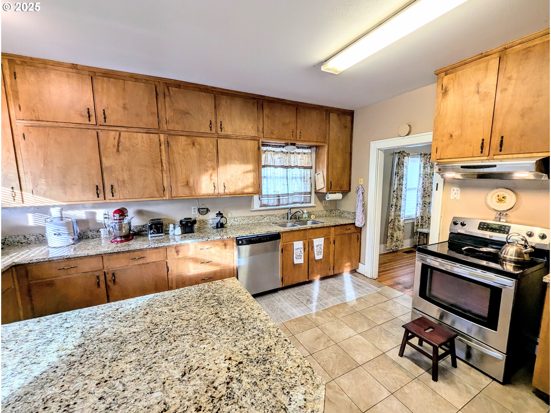 1302 9th Street La Grande, OR 97850 - Photo 6 of 15 a kitchen with stainless steel appliances granite countertop a stove a sink dishwasher a microwave oven and a dining table with wooden cabinet