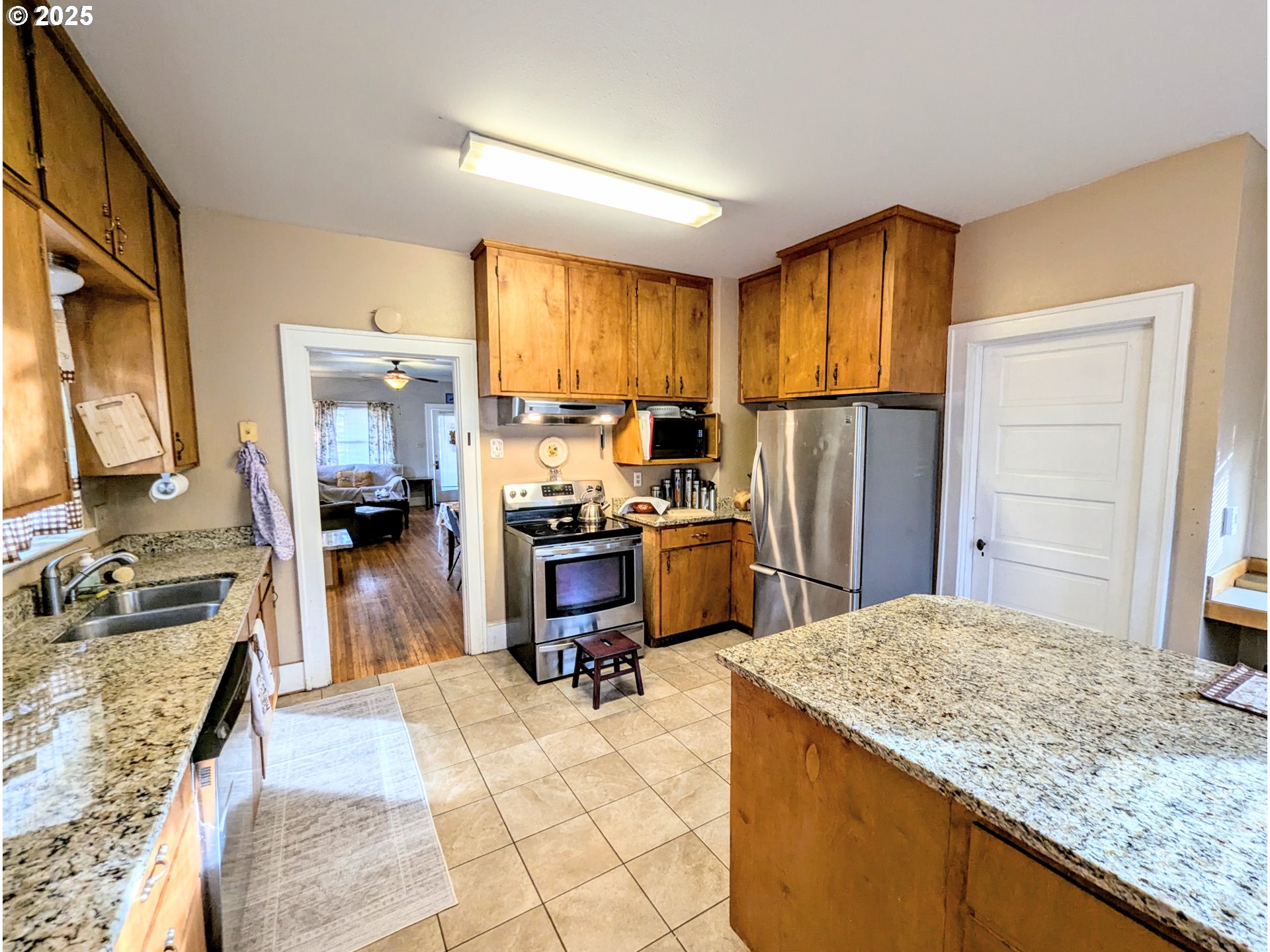1302 9th Street La Grande, OR 97850 - Photo 7 of 15 a kitchen with kitchen island granite countertop a sink stove and refrigerator