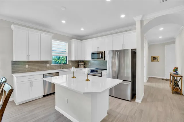 a large white kitchen with a sink and stainless steel appliances