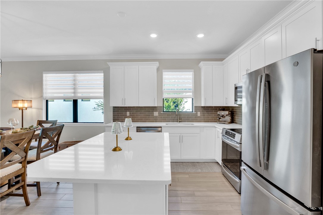5292 Unity Square Vero Beach, FL 32967 - Photo 8 of 36 a kitchen with a refrigerator a stove a sink and white cabinets with wooden floor
