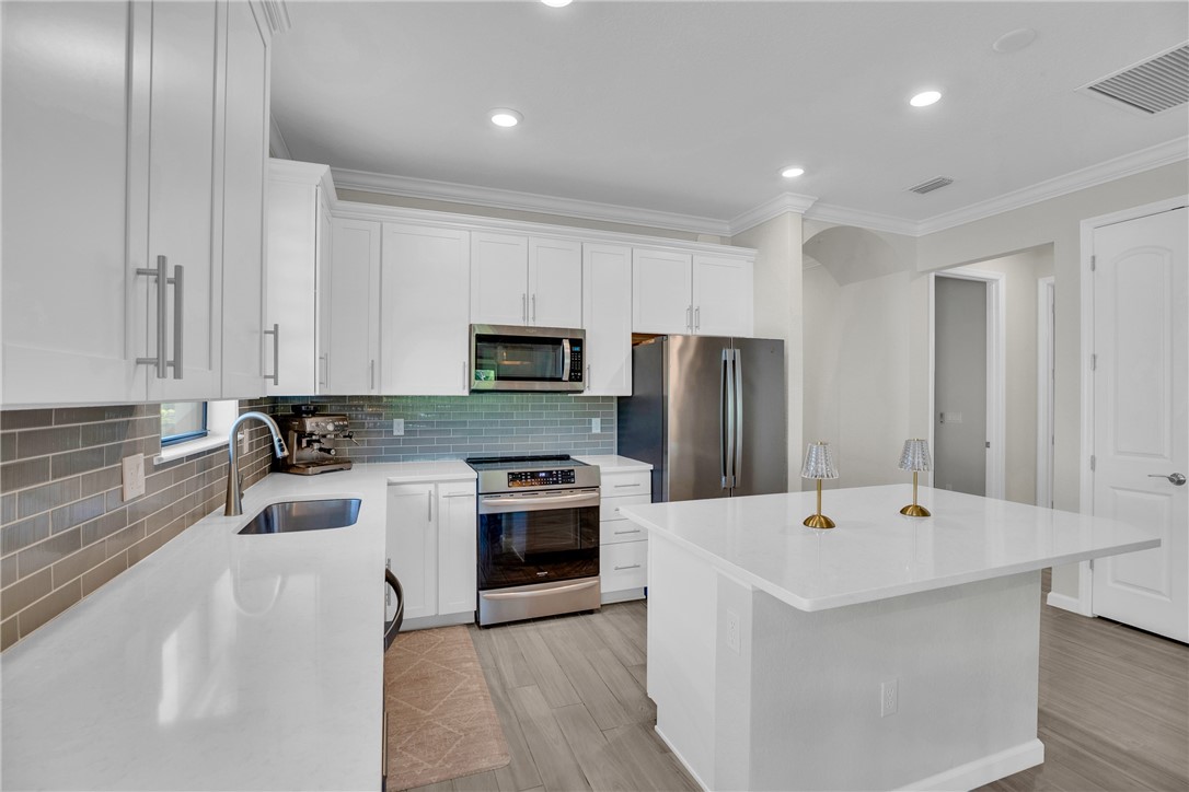 5292 Unity Square Vero Beach, FL 32967 - Photo 9 of 36 a large white kitchen with a sink and stainless steel appliances