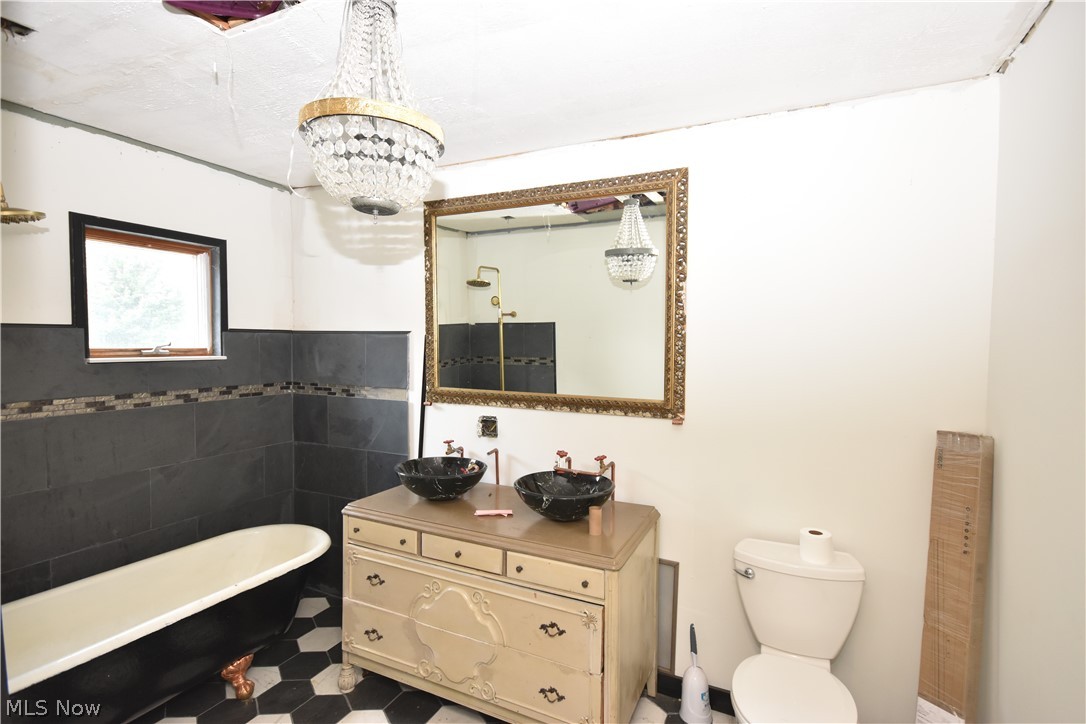 5694 Middle Ridge Road Madison, OH 44057 - Photo 10 of 27 Bathroom with a bath, tile walls, tile floors, toilet, and vanity