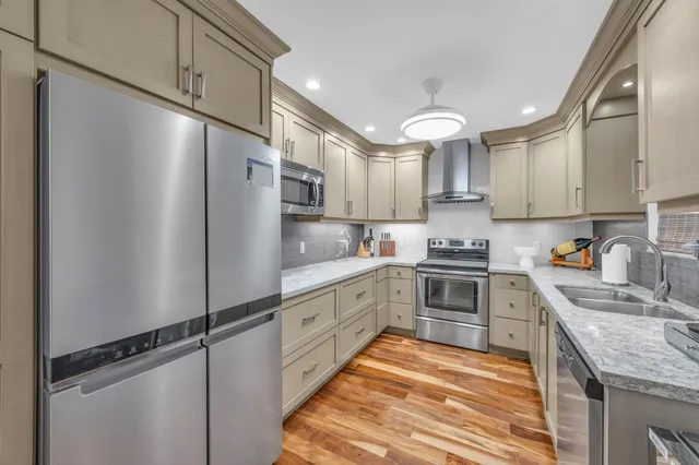 a kitchen with granite countertop a refrigerator stove top oven and cabinets