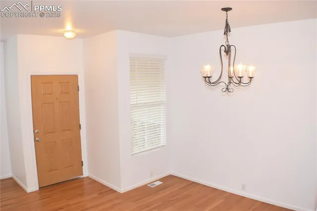a view of a room with wooden floor and way to kitchen