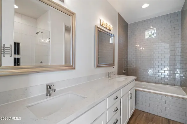 a bathroom with a sink double vanity granite tub shower and a mirror