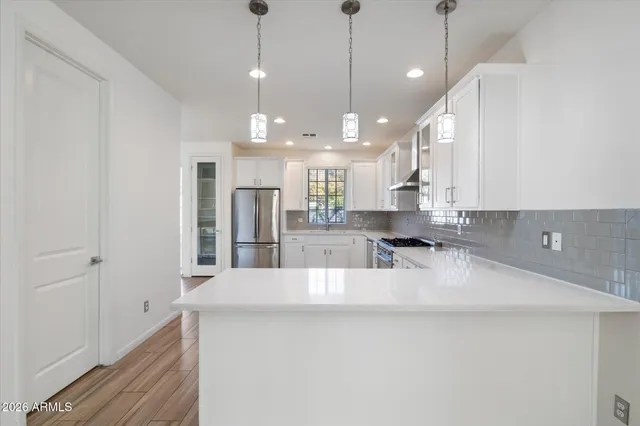 a large kitchen with granite countertop a large kitchen island white cabinets and stainless steel appliances