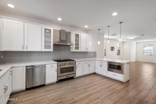 a large kitchen with stainless steel appliances granite countertop a stove a sink dishwasher and a oven with white cabinets