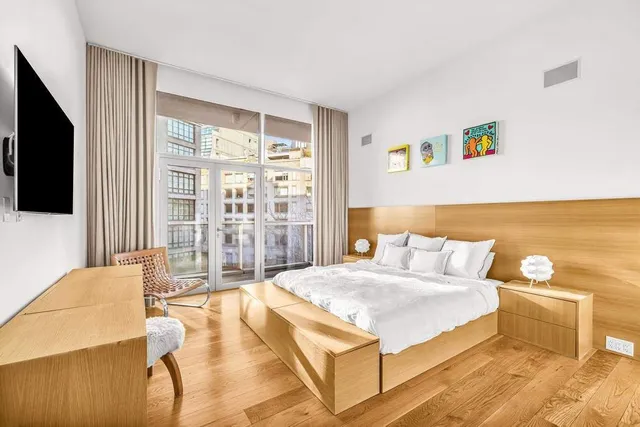 a spacious bedroom with a bed and a flat screen tv