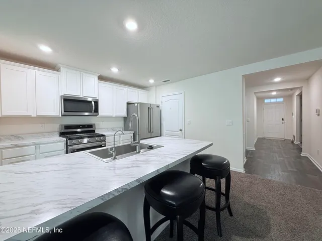 a kitchen with stainless steel appliances granite countertop a table chairs sink refrigerator and microwave