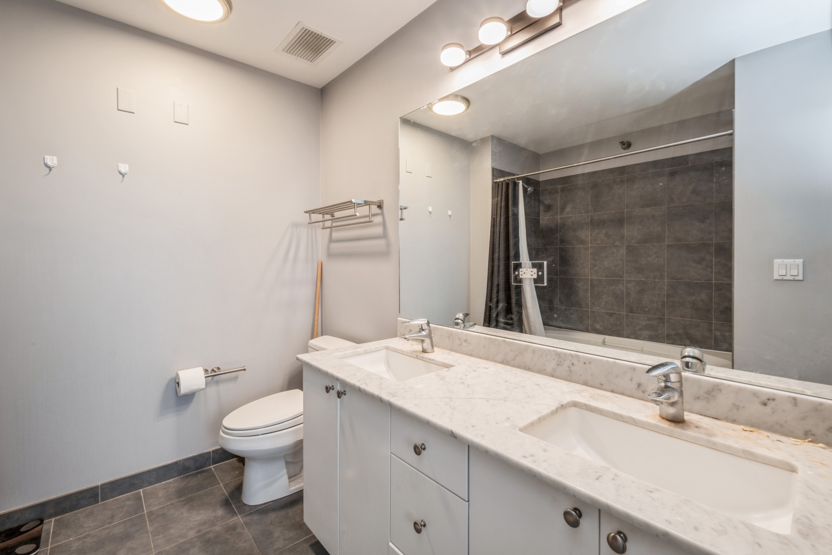 235 West Van Buren Street, Unit 4214 Chicago, IL 60607 - Photo 8 of 16 a bathroom with a granite countertop sink a toilet and a mirror