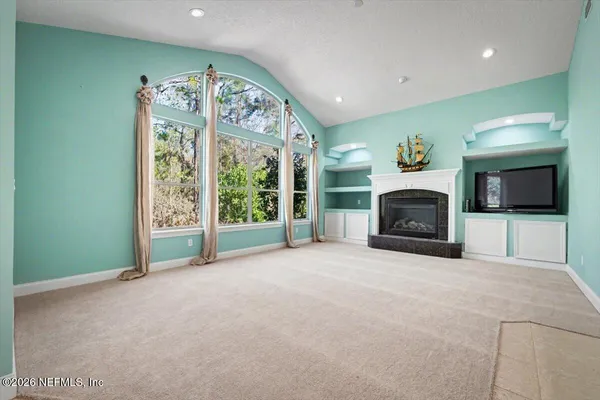 an empty room with windows and fireplace
