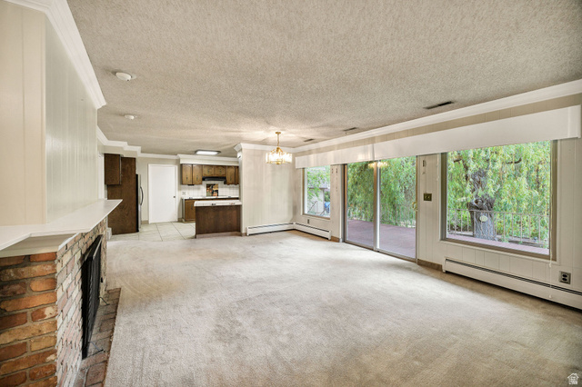 1365 Sumac Drive Logan, UT 84321 - Photo 15 of 66 Open-concept living area featuring a brick fireplace with a white mantel, sliding glass doors, large windows, and an integrated kitchen with wood cabinetry