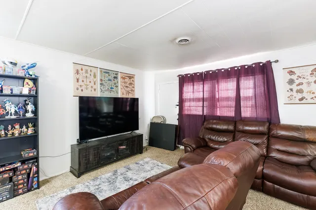 a living room with furniture a flat screen tv and a floor to ceiling window
