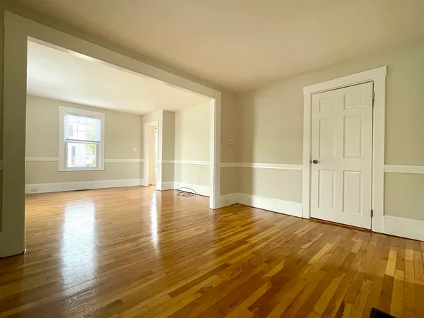 an empty room with wooden floor and windows with curtains