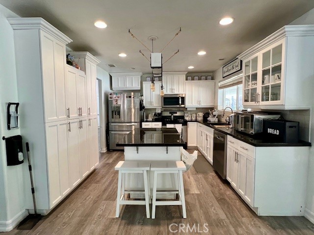 16630 Arabian Avenue Riverside, CA 92504 - Photo 13 of 42 a kitchen with stainless steel appliances a refrigerator a stove a sink dishwasher a oven with white cabinets and wooden floor