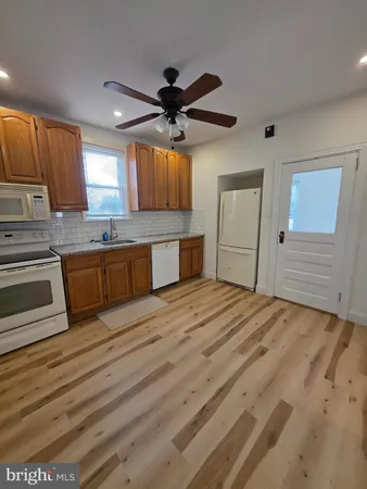 a kitchen with stainless steel appliances granite countertop a sink cabinets and wooden floor