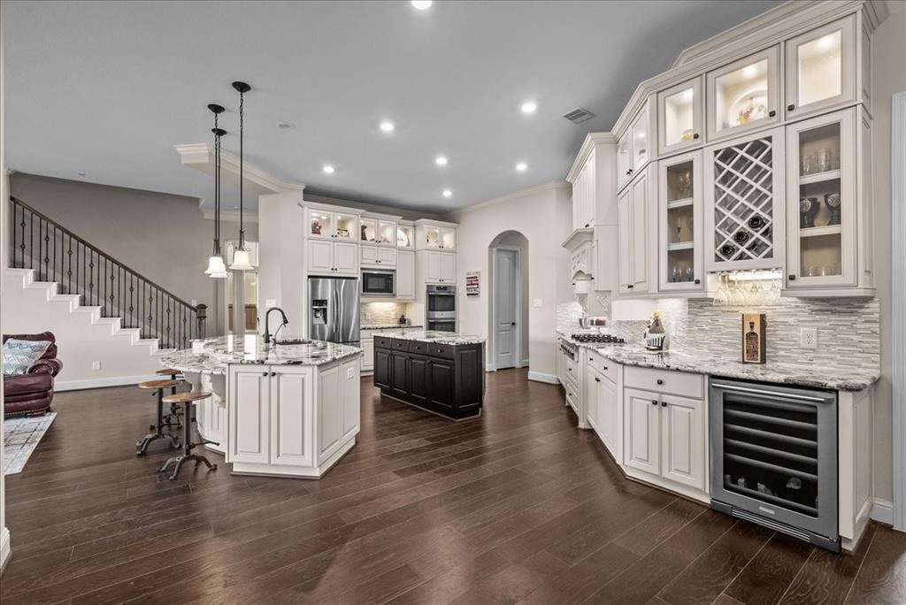 a kitchen with stainless steel appliances kitchen island granite countertop a stove a sink and a wooden floors