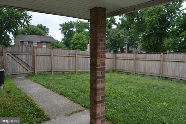 a view of a backyard with wooden fence and large trees