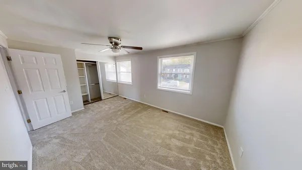 an empty room with windows and fan