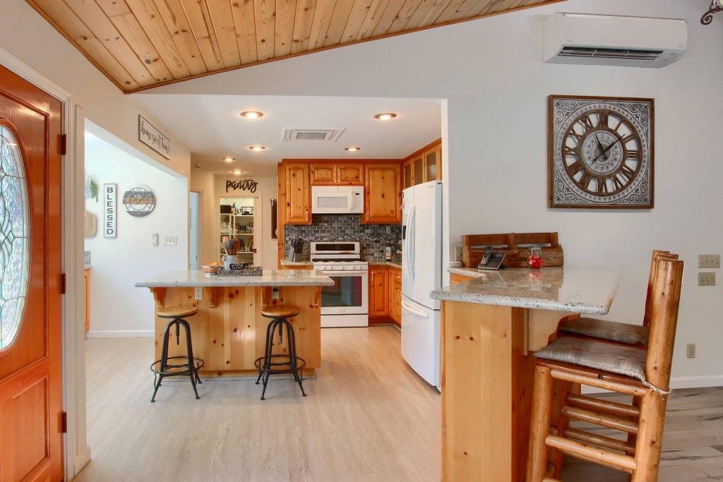 50537 Cedar Valley Drive Oakhurst, CA 93644 - Photo 8 of 59 a open kitchen with stainless steel appliances kitchen island granite countertop a table chairs and a refrigerator