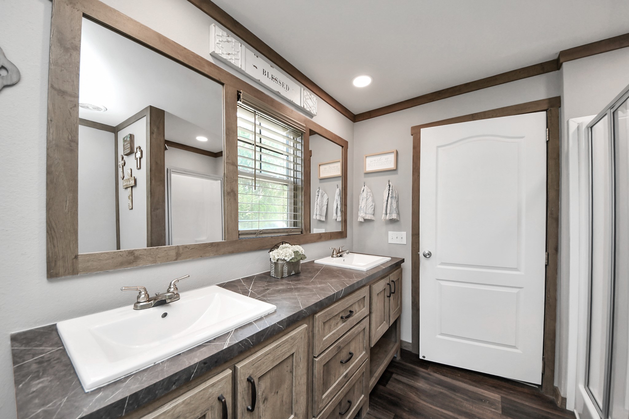 131 Kiowa Court Rosharon, TX 77583 - Photo 20 of 42 This bathroom features a dual-sink vanity with a dark countertop, large mirror, and ample storage. The wood accents and neutral color palette create a warm, inviting atmosphere.