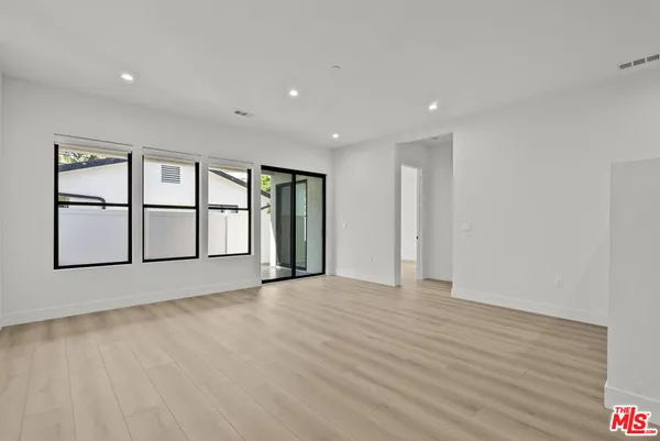 a view of an empty room with window and wooden floor