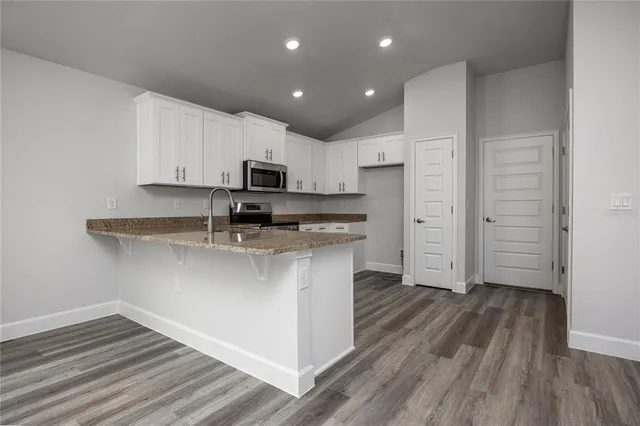 a kitchen with stainless steel appliances granite countertop a sink a stove and a refrigerator