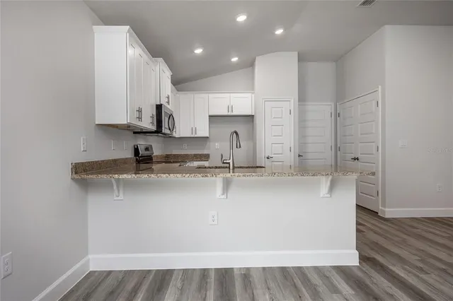 a kitchen with stainless steel appliances granite countertop a stove top oven a sink and white cabinets