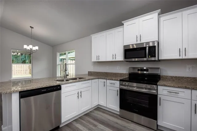 a kitchen with stainless steel appliances granite countertop a stove a sink and a microwave